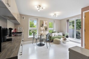 Eine moderne Küche mit Essbereich, einem grünen Sofa und großen Fenstern.