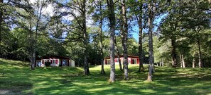 Un edificio rojo rodeado de un área boscosa y un primer plano con césped.