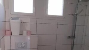 A bathroom with a toilet, a sink, and a shower area.