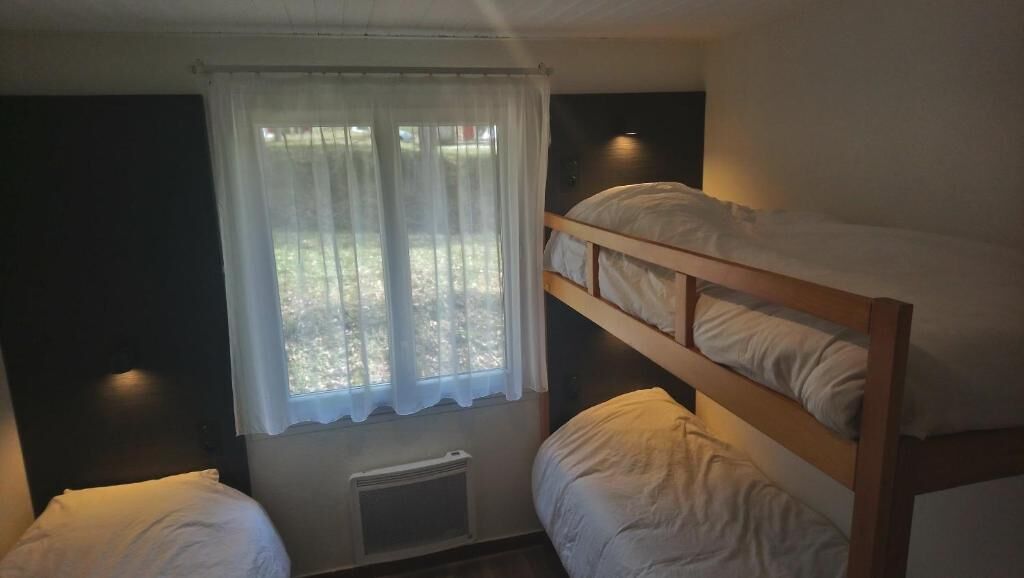 A bunk bed room with a window and a radiator.