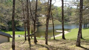 A lakeside park with trees, a bench, and a small building.