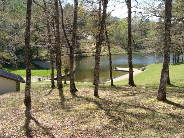 A lakeside park with trees, a bench, and a small building. - Le Vendahaut Résidence de tourisme (Lapleau)