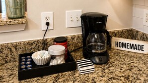 Una cuina amb una cafetera, un pot i un safata amb coses damunt del taulell.
