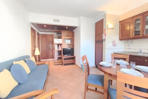Ein modernes Wohnzimmer mit Sofa, TV-Schrank, Esstisch und Küchenzeile.