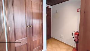 Een gang met houten deuren, een brandblusser en een bord aan de muur.