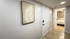 A hallway with a door leading to a bedroom with a bed. - Historic Barn View | Cozy Ground Level Retreat (Frelinghuysen Township)