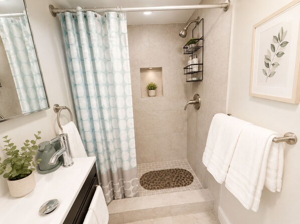 Un baño con ducha, lavabo con espejo y toallero.