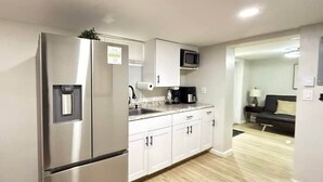 A modern kitchen with stainless steel appliances, white cabinetry, and a wooden floor. - Historic Barn View | Cozy Ground Level Retreat (Frelinghuysen Township)