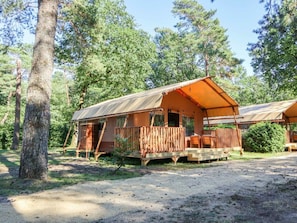 Eine rustikale Holzhütte mit einer Holzdiele, umgeben von Bäumen.
