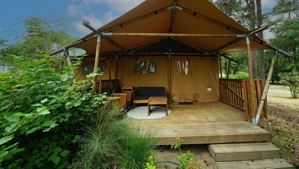 A wooden structure with a covered porch and a bench, surrounded by greenery. - Holiday Home in Otterlo With Terrace (Otterlo)