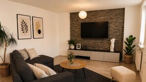 Ein modernes Wohnzimmer mit einer Couch, einem Couchtisch und einem flachbildfernseher, der an einer strukturierten Wand angebracht ist.