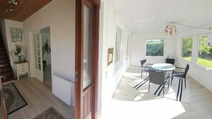 Ein Zimmer mit Treppe, Heizkörper, Essbereich mit Tisch und Stühlen sowie großen Fenstern.