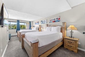 Ein Hotelzimmer mit zwei Betten, einem Fernseher, einer Lampe und Kunstwerken an den Wänden.