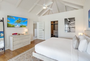 A bedroom with a bed, a dresser, a ceiling fan, and artwork on the walls. - Peace & Happiness Anguilla (Cul du Sac)