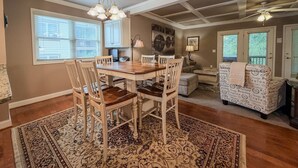 A dining area with a wooden table and chairs, a chandelier, and a patterned rug. - Helen Riverfront Escape | Walk to Downtown (Helen)