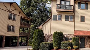 A two-story building with a balcony, a stone foundation, and a garage. - Helen Riverfront Escape | Walk to Downtown (Helen)