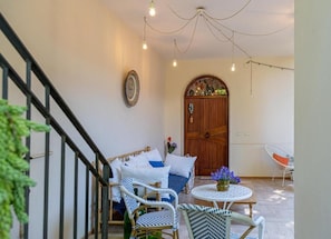 Un cuarto acogedor con una cama, dos sillones de mimbre, una pequeña mesa redonda y una puerta de madera con un arco decorativo.