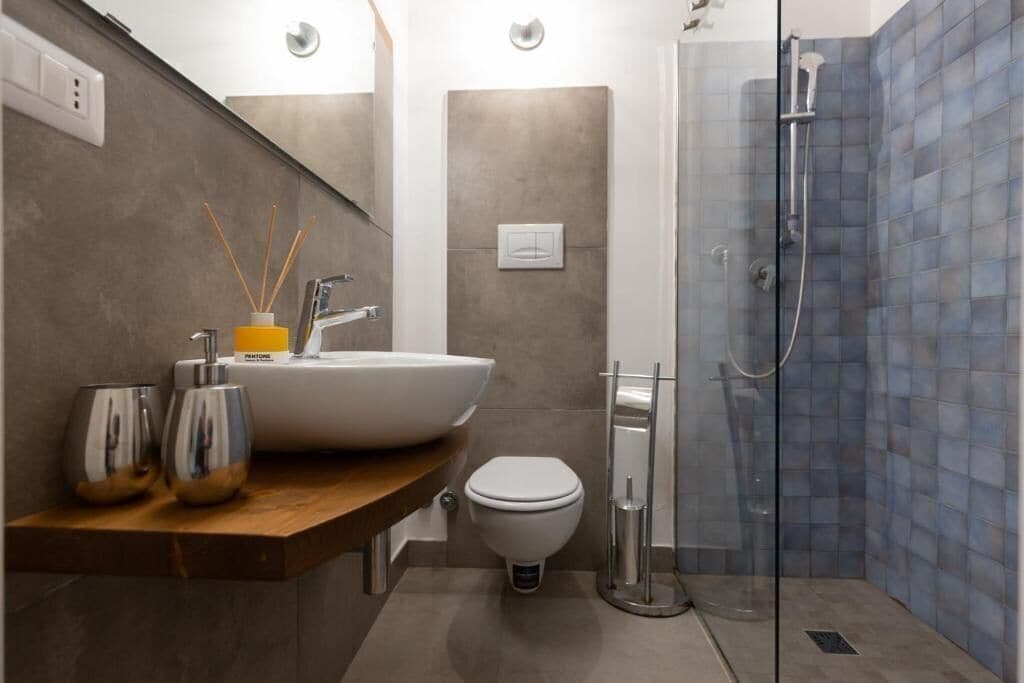 Un bagno moderno con un lavabo a incasso, un water e una cabina doccia in vetro.