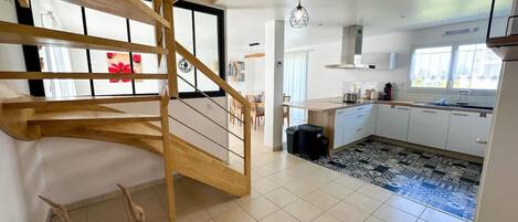 Una cocina moderna con escalera de madera, suelo de baldosas y alfombra estampada.