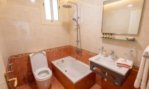 Une salle de bain équipée de toilettes, d’une baignoire et d’une douche.