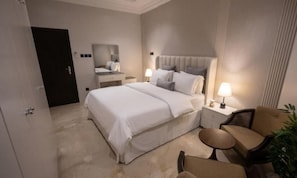 A hotel room with a bed, bedside tables, a chair, and a small table.