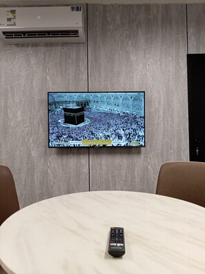 Un televisor montado en la pared muestra una multitud en un lugar religioso importante.