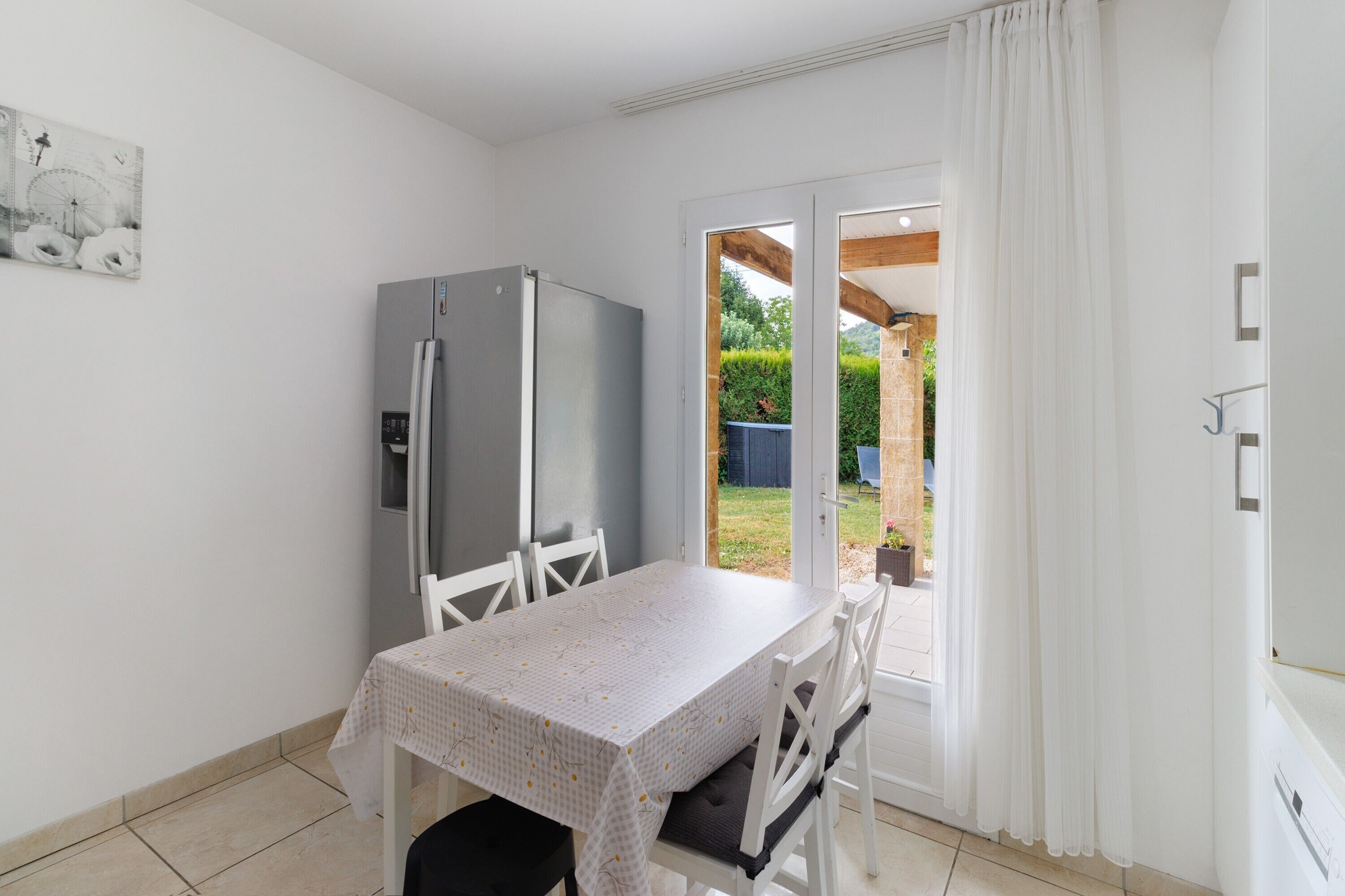 A compact kitchen with a refrigerator, a dining table with chairs, and a sliding glass door leading to an outdoor area.