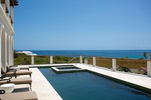 Ein Pool mit Blick auf den Ozean, Liegestühle und eine Holzterrasse.