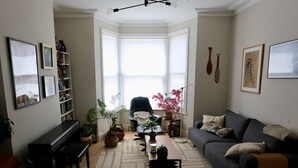 A living room with a piano, sofa, coffee table, and potted plants. - Stunning house and garden - the perfect London base for your family vacation (London)