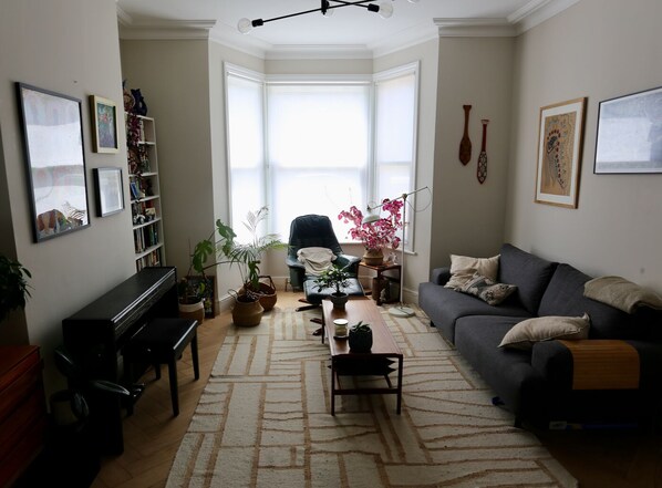 Ein Wohnzimmer mit Klavier, Sofa, Couchtisch und Topfpflanzen.