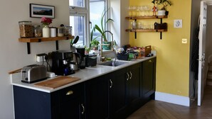 A kitchen with a large island, a window, and a yellow accent wall. - Stunning house and garden - the perfect London base for your family vacation (London)