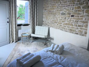 Ein Schlafzimmer mit Bett, Stuhl, Steinwand und Tür.