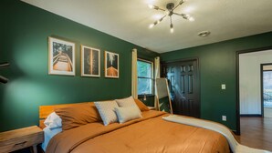 A bedroom with a large bed, a nightstand, a ceiling fan, and framed pictures on the wall. - Moonstone | Hocking Hills, Modern, Hot Tub (Rockbridge)