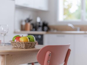 Eine Küche mit einem Holztisch, einem Korbfruchtkorb und einem rosa Stuhl.