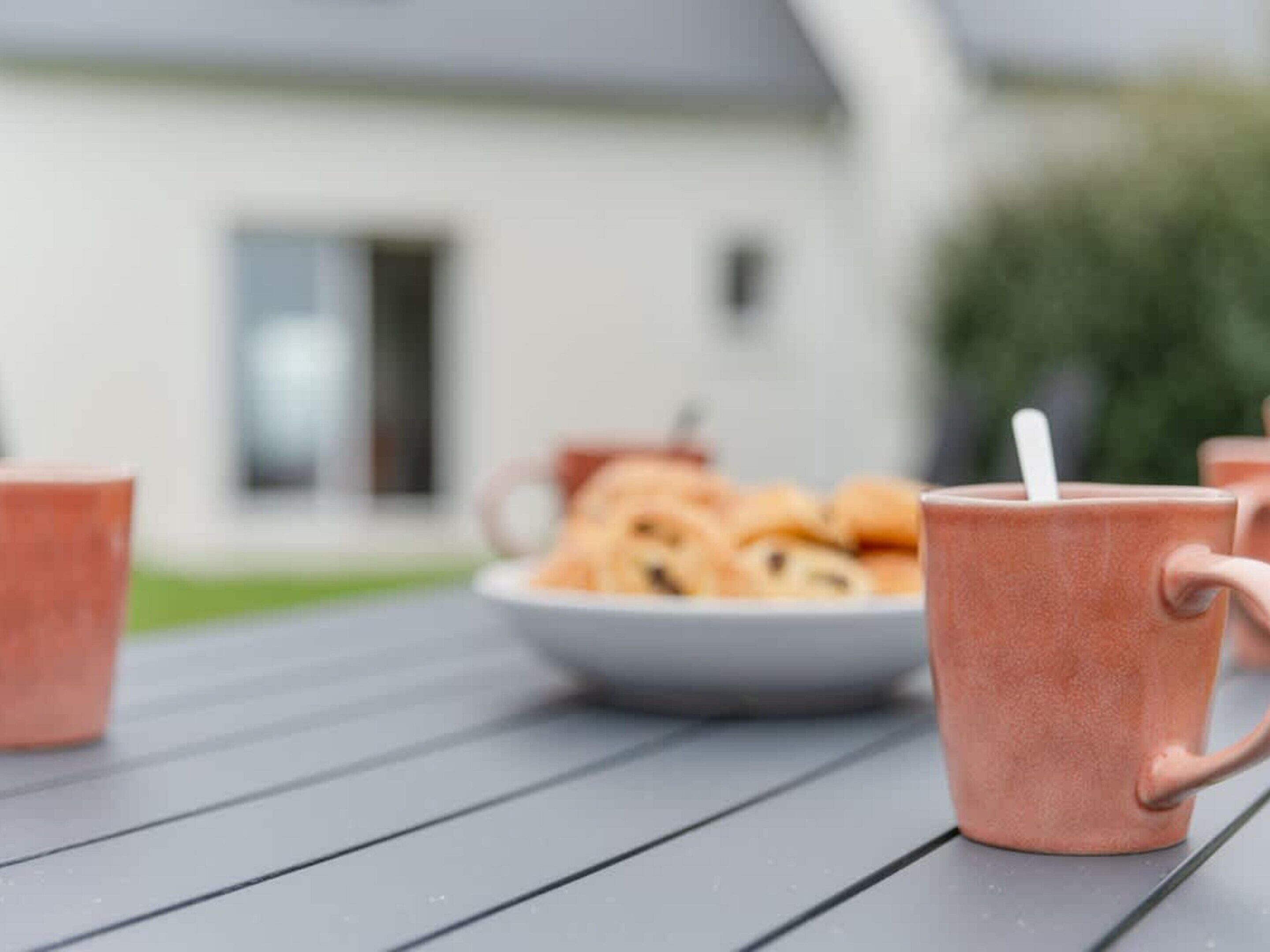 A table with a plate of cookies and a mug with a straw.