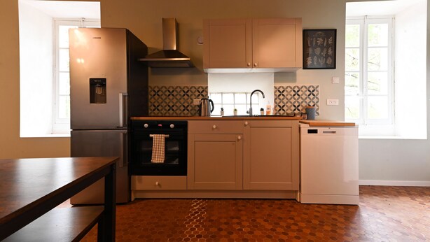 A kitchen with a stainless steel refrigerator, oven, and dishwasher, wooden cabinets, a tiled backsplash, and a window providing natural light. - A peaceful family retreat surrounded by nature - 6-bedroom apartment (Mazerolles-du-Razès)