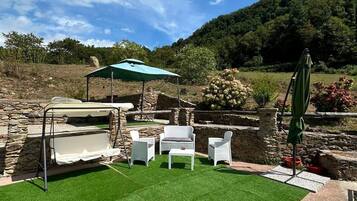 Un espacio al aire libre con césped artificial, paredes de piedra y mobiliario exterior.