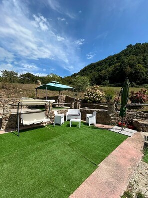 A patio area with artificial grass, stone walls, and outdoor furniture.