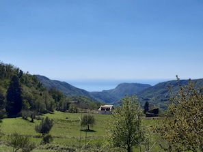 A rural landscape with rolling hills, a small building, and a clear sky.