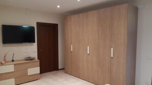 Une chambre à coucher avec un lit, une armoire, un téléviseur et une commode.