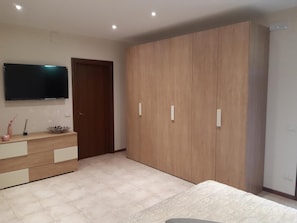 A bedroom with a bed, a wardrobe, a TV, and a dresser.