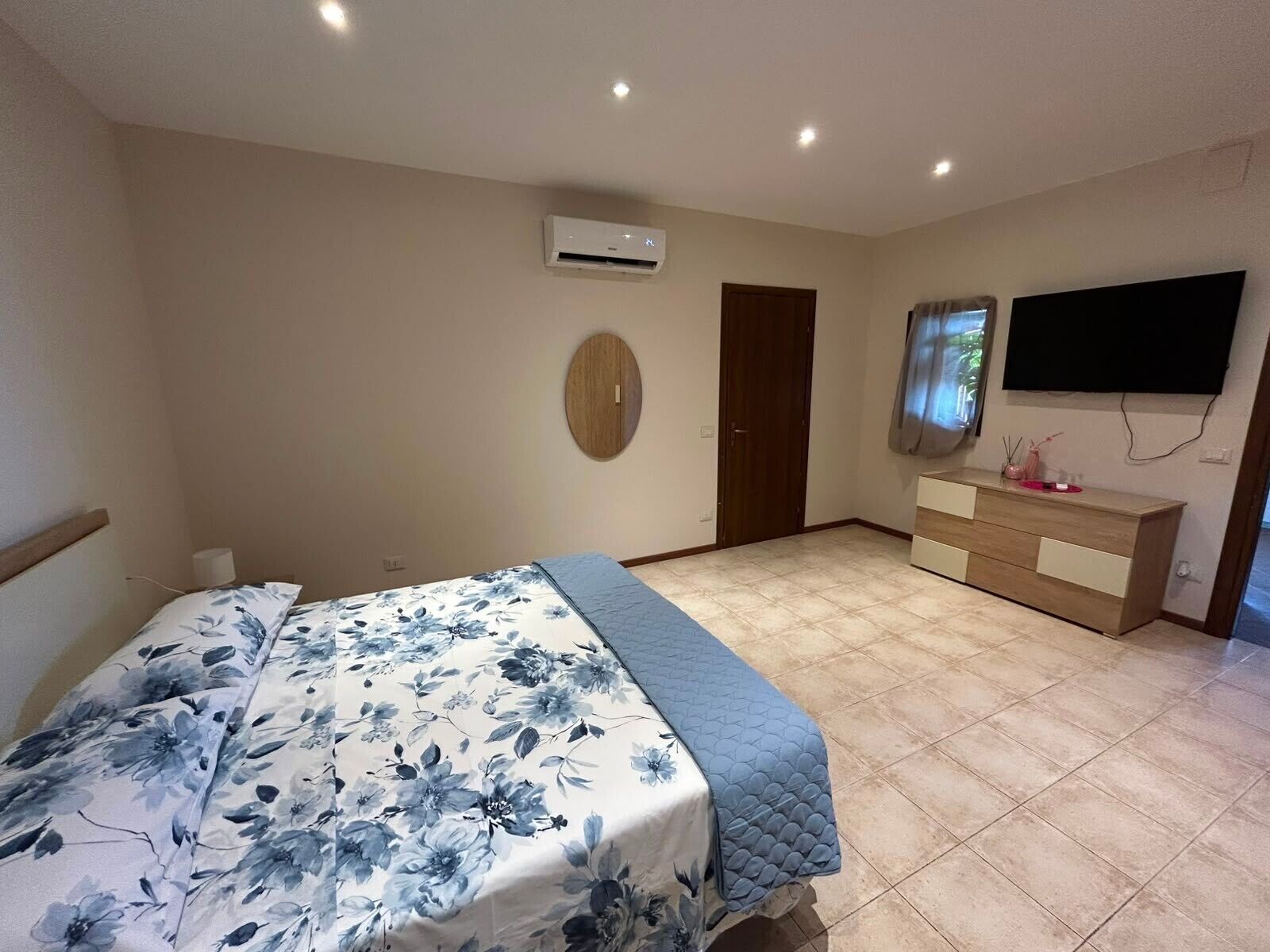 Un dormitorio con una cama, un aparador, un televisor y un equipo de aire acondicionado.