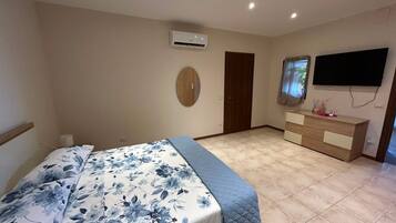 Un dormitorio con una cama, un aparador, un televisor y un equipo de aire acondicionado.