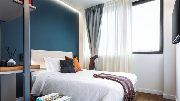 Una camera da letto moderna con un letto, un comodino e una finestra con tende.