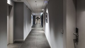 Un corridoio moderno di un hotel, con un lungo percorso lineare, illuminazione a scomparsa e una porta dotata di serratura a codice.
