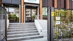 L'ingresso di un hotel con un cartello che riporta 'C99 HOTEL & RESIDENCE', una scala e un cancello con il cartello 'C99'.