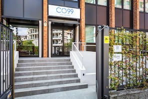 A hotel entrance with a sign reading 'C99 HOTEL & RESIDENCE,' a staircase, and a gate with a 'C99' sign.
