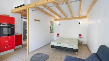 A compact room with a kitchenette, a bed, a small table, and a sofa.