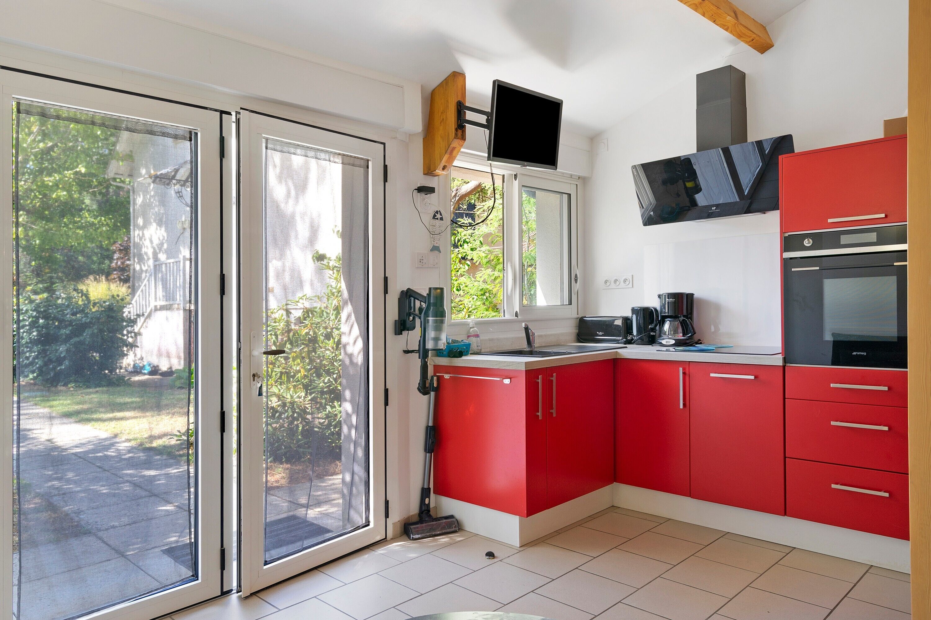 A kitchen with red cabinets, a built-in oven, a microwave, and a large window.