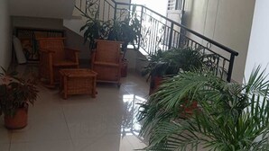 A spacious indoor area with a staircase, wicker furniture, and potted plants. - Hotel Casa Grande  (Agustín Codazzi)
